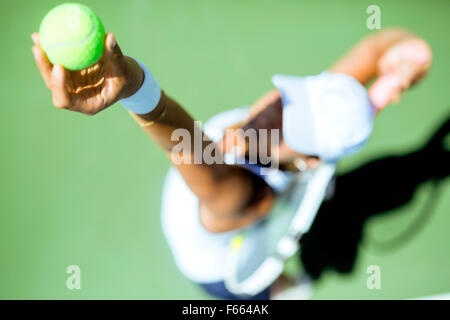 Beautiful female tennis player serving outdoor and a closeup of the serve from above Stock Photo