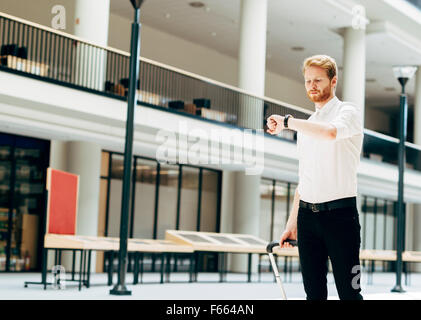 Handsome business holding a trolley and walking in a modern building Stock Photo
