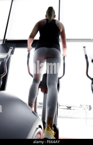 Closeup shot of legs of a female using elliptical trainer in a gym Stock Photo