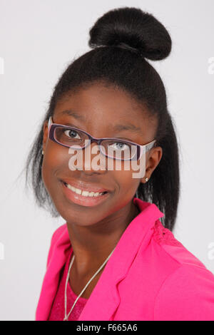 Portrait of a young African American girl wearing a pink shirt and glasses on a white backdrop. Stock Photo