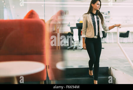 Beautiful woman using stairs in an office and smiling Stock Photo