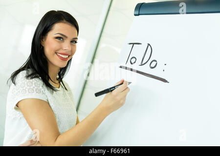 Beautiful, young, businesswoman writing todo onto a white writing board
