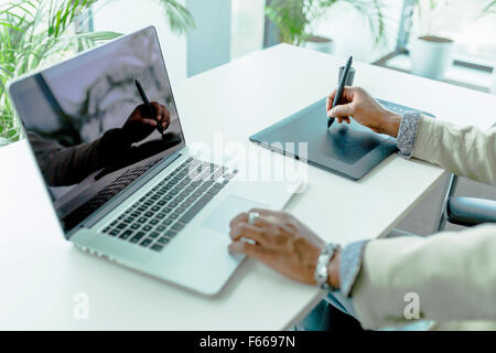 Graphics designer using digitizer with its reflection showing on the notebook screen Stock Photo