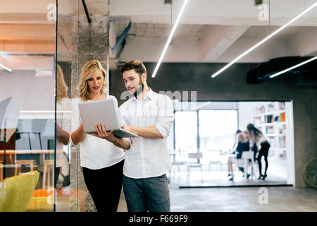 Coworkers looking at notebook in a modern office Stock Photo