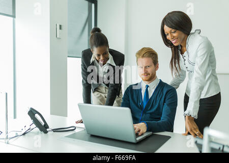 Business people talking and smiling in an office in front of a notebook Stock Photo