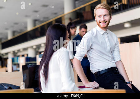 A group of academics studying in the library and conversing in a positive mood Stock Photo