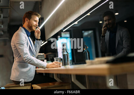 Busy businessman talking on phone while sitting in a pub Stock Photo
