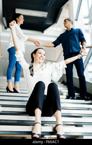 Group of business people shaking hands on stairs in a beautiful modern office and being happy Stock Photo