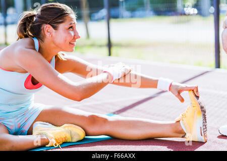 Beautiful young athletic woman stretching in summer before running Stock Photo