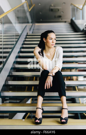 Businesswoman sitting on stairs and thinking. Fashion style photo Stock Photo