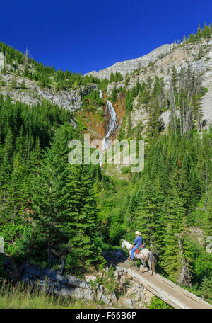 horse rider below waterfall on trail to headquarters creek pass along the rocky mountain front near choteau, montana Stock Photo