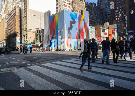 People cross Eighth Avenue and West 34th Street in New York past a building with a painted construction shed, slated for development on Tuesday, November 3, 2015.  (© Richard B. Levine) Stock Photo