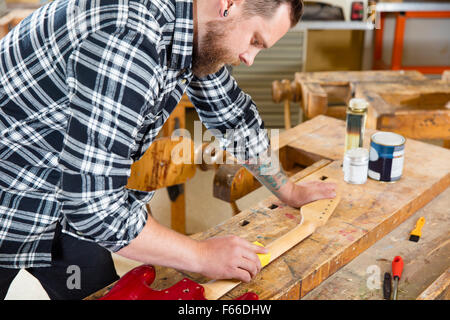 Craftsman sanding a guitar neck in wood at workshop Stock Photo