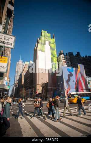 People cross Eighth Avenue and West 34th Street in New York past a building with a painted construction shed, slated for development, with an unfinished billboard above it. on Sunday, November 8, 2015.  (© Richard B. Levine) Stock Photo