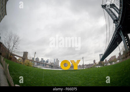 The bright yellow OY/YO public art sculpture in Brooklyn Bridge Park in New York on Thursday, November 12, 2015. OY/YO by the artist Deborah Kass debuts in Brooklyn Bridge Park. Seen from Brooklyn the sculpture evokes the Yiddishism 'OY' while seen from the Manhattan facing side it reads 'YO', evoking the New York colloquialism of calling out to someone. The 8X17 1/2 foot sculpture will be on view until August 2016. (© Richard B. Levine) Stock Photo