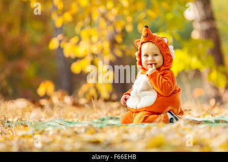 Cute baby boy dressed in fox costume in autumn park Stock Photo