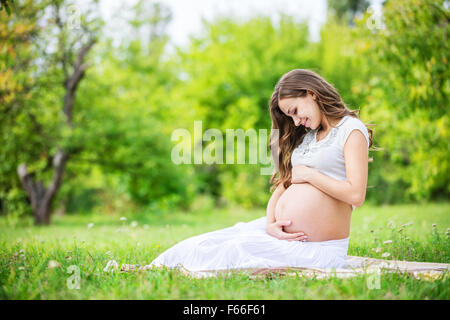 Beautiful pregnant woman relaxing outside in the park Stock Photo