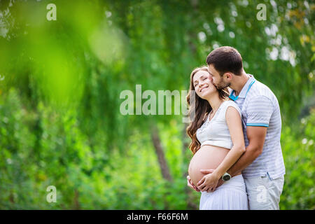 Happy young couple expecting baby in summer park Stock Photo