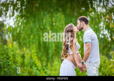 Happy young couple expecting baby in summer park Stock Photo