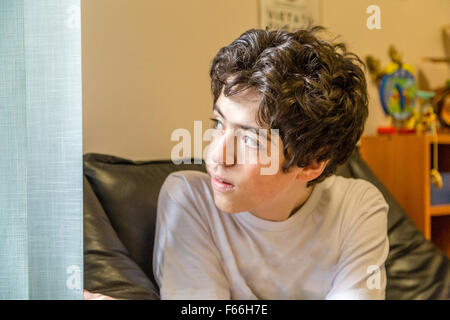 Caucasian teenage boy waits in the waiting room in the medical office and looks out of the window Stock Photo