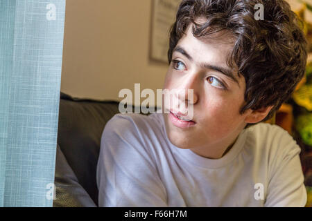 Caucasian teenage boy waits in the waiting room in the medical office and looks out of the window Stock Photo