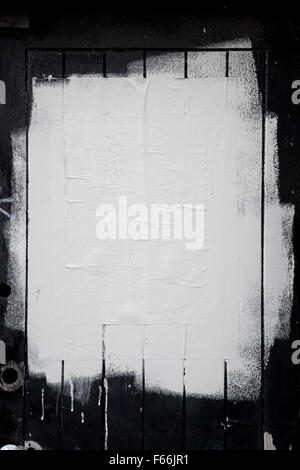 Rough white paint rolled over a black wooden textured background Stock Photo