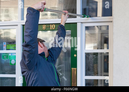 Window cleaning. Window cleaner cleaning windows of a business, Nottingham, England, UK Stock Photo