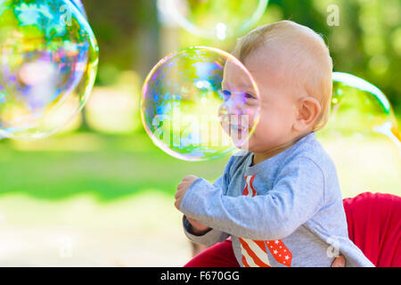 Cute baby catching soap bubbles in a summer day Stock Photo