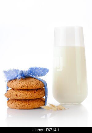 Stack of three homemade oatmeal cookies tied with blue ribbon in small white polka dots, ear of oats and glass of milk, isolated Stock Photo