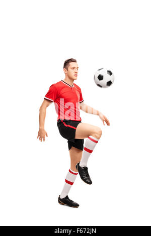 Full length portrait of a young football player juggling a ball on his knees isolated on white background Stock Photo