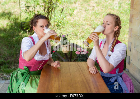 Drink Two women in Bavarian Dirndl with a beer