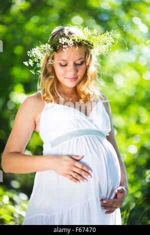 Pregnant woman in green forest Stock Photo