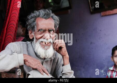 Elderly Indian man smiles from the window of his home Stock Photo