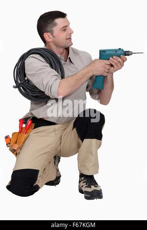 Tradesman holding up an electric screwdriver Stock Photo