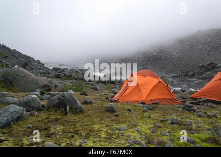 two orange tents on the bank of the rough river Stock Photo