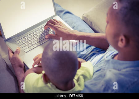 Father and son using laptop on the couch Stock Photo
