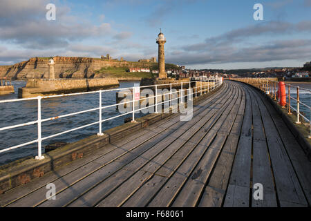 Scenic view of lighthouses, harbour entrance, West Pier, Abbey & St. Mary's Church on sunlit cliffs Summer evening, Whitby, North Yorkshire, GB, UK. Stock Photo