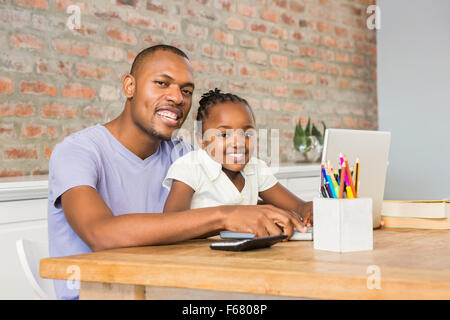 Cute daughter using laptop at desk with father Stock Photo