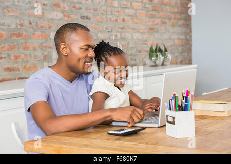 Cute daughter using laptop at desk with father Stock Photo