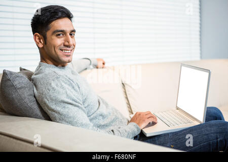 Handsome man using laptop on sofa Stock Photo