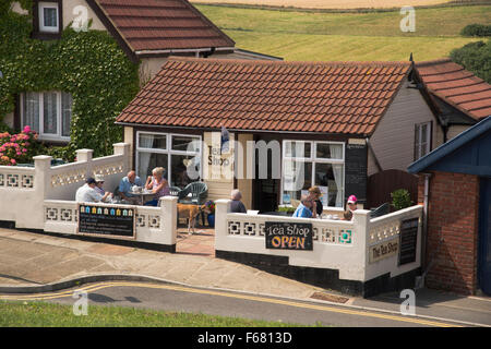 People sitting outside, on the small terrace at The Tea Shop, relaxing & enjoying cups of tea – Staithes, North Yorkshire, UK, on a sunny summer day. Stock Photo