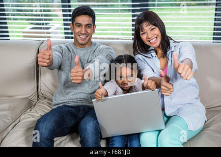 Happy young family using laptop with thumbs up Stock Photo