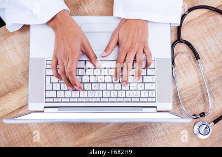Doctor using laptop on wooden desk Stock Photo
