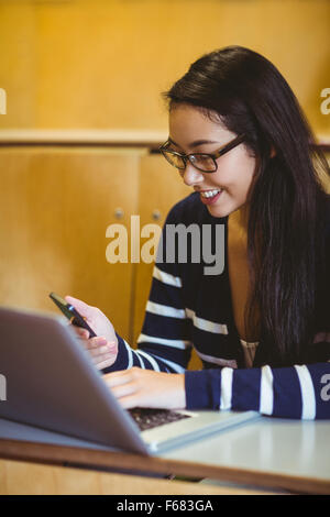 Smiling student using laptop and smartphone during class Stock Photo
