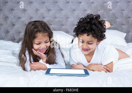 Cute siblings using tablet on the bed Stock Photo