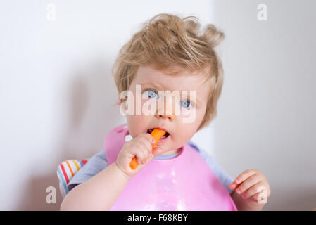 One year old baby eating a healthy carrots and vegetables Stock Photo