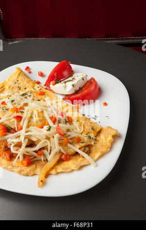 Breakfast served on a white plate, eggs, cheese,  tomatoes Stock Photo