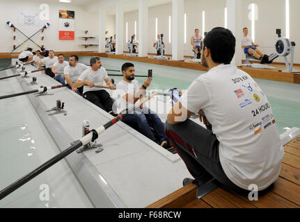 The third team consisting of ten rowers taking their turn at ten ergometers during a 24-hour rowing marathon in a gymnasium of the Jacobs University in Bremen, Germany, 14 November 2015. Several refugees from a shelter located nearby that have gathered for the third hour of this event are receiving rowing instructions from a coach. The participants will cover a distance of 3078 kilometres in the event, which roughly equals the length of the perilous escape route from Damascus, Syria, across the Mediterranean Sea to Europe. 70 participants will take turns every hour to complete the challenge. P Stock Photo