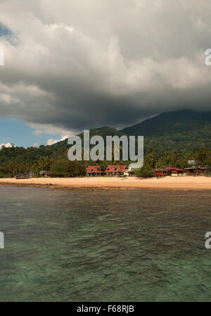 Malaysia,Tioman Island in summer.View from ocean on the beach and homes in  Paya Beach Resort.In the background visible forested Stock Photo