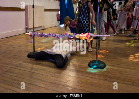 Horizontal portrait of young girls participating in a 'limbo' competition at a birthday party. Stock Photo